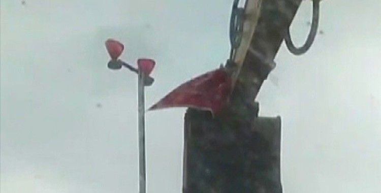 Antalya'da bir vatandaş rüzgarda kopmak üzere olan Türk bayrağını kepçeye çıkarak yerinden aldı