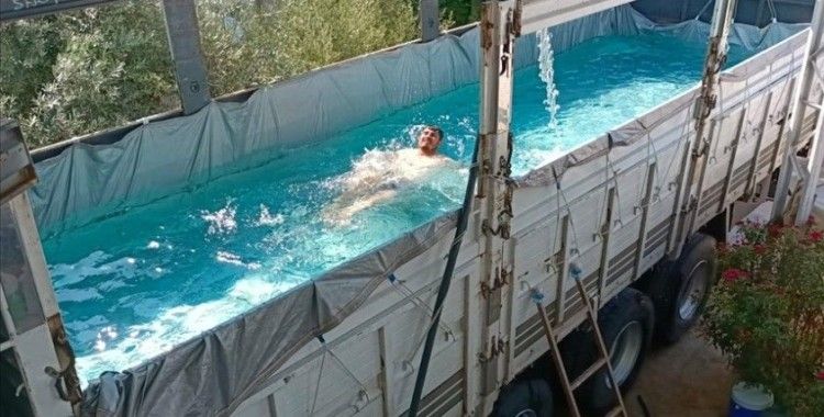 Antalya'da sıcak hava ve nemden bunalan çiftçi, havuza çevirdiği kamyonunun kasasında serinledi